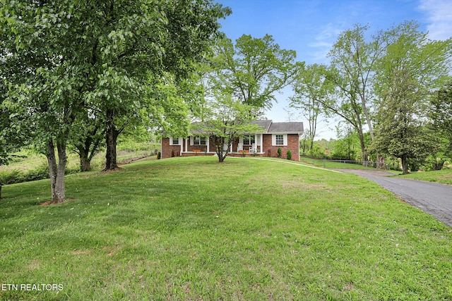 ranch-style house with a front yard, covered porch, and brick siding