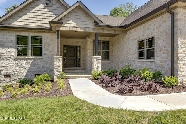 property entrance featuring stone siding and a shingled roof