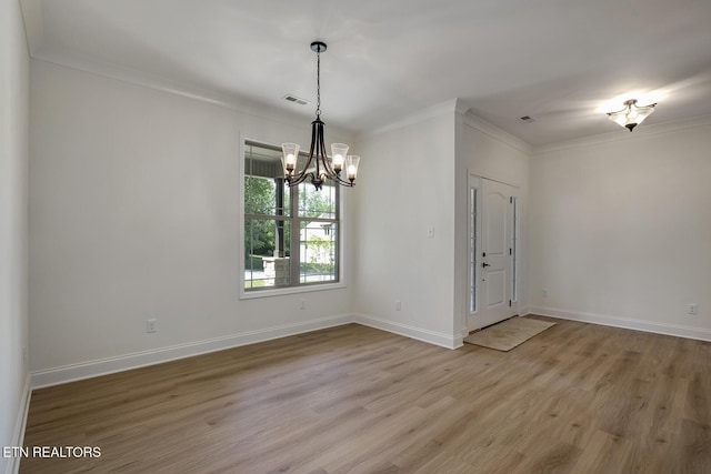 empty room featuring a chandelier, light wood finished floors, crown molding, and baseboards