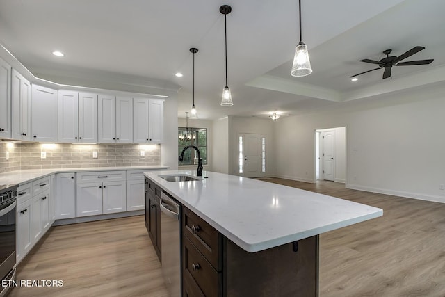 kitchen featuring a sink, light wood finished floors, stainless steel appliances, backsplash, and ornamental molding