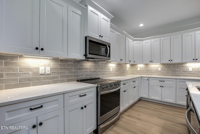 kitchen with stainless steel appliances, white cabinetry, light stone countertops, backsplash, and recessed lighting