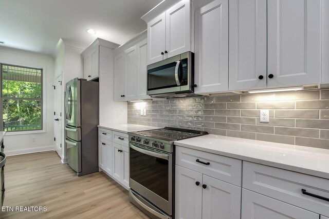 kitchen with appliances with stainless steel finishes, light wood-style floors, white cabinetry, light stone countertops, and recessed lighting