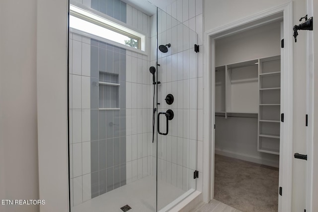 bathroom with a shower stall and a walk in closet