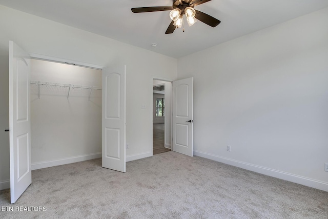 unfurnished bedroom with carpet floors, a closet, baseboards, and a ceiling fan