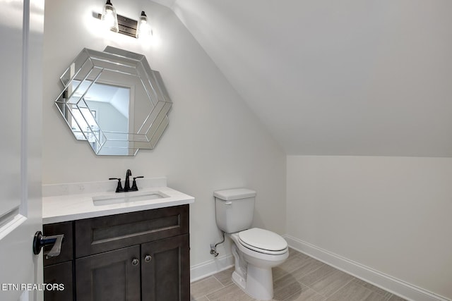 bathroom featuring vaulted ceiling, vanity, toilet, and baseboards