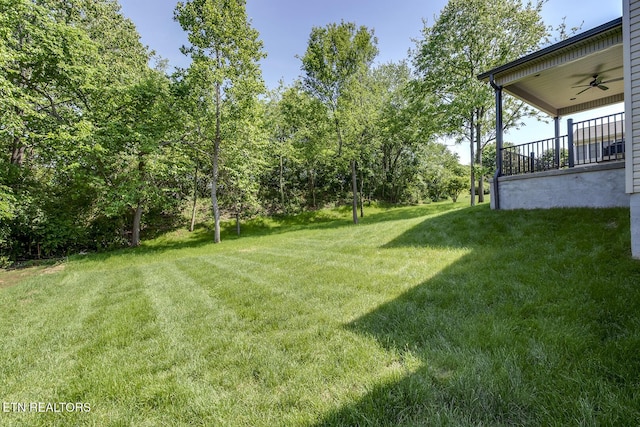 view of green lawn featuring ceiling fan