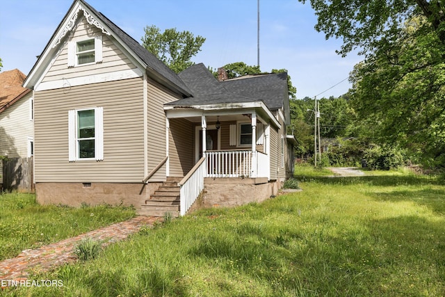 view of front of house featuring a porch, a front lawn, roof with shingles, and a chimney