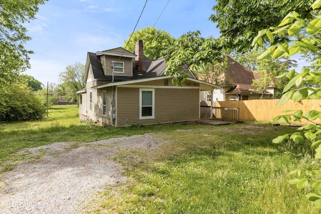 rear view of house with fence, a chimney, and a yard