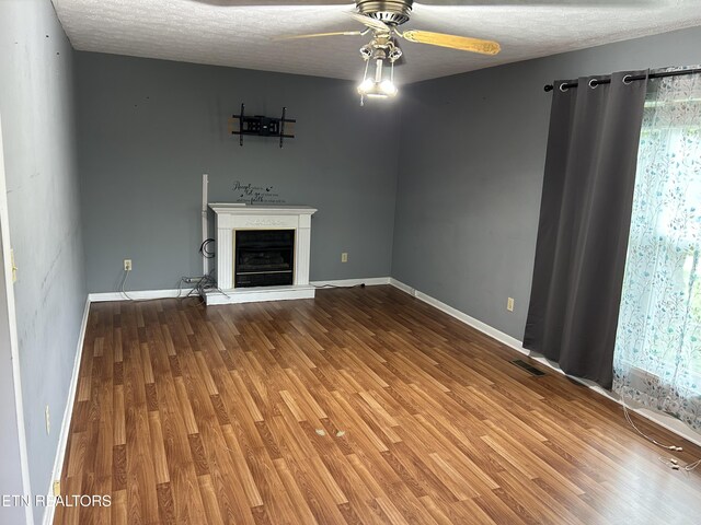 131 Oak Hill Dr, Jamestown, TN 38556 - unfurnished living room with a fireplace with raised hearth, a ceiling fan, visible vents, and wood finished floors