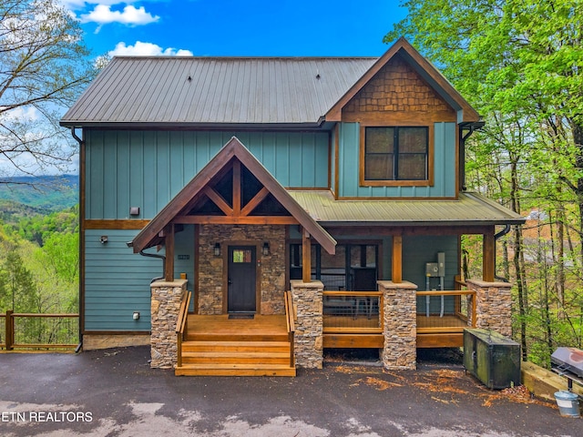 view of front of property with a porch, stone siding, and metal roof