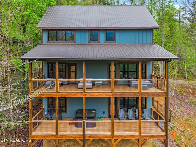 back of house with a wooden deck, a balcony, and metal roof