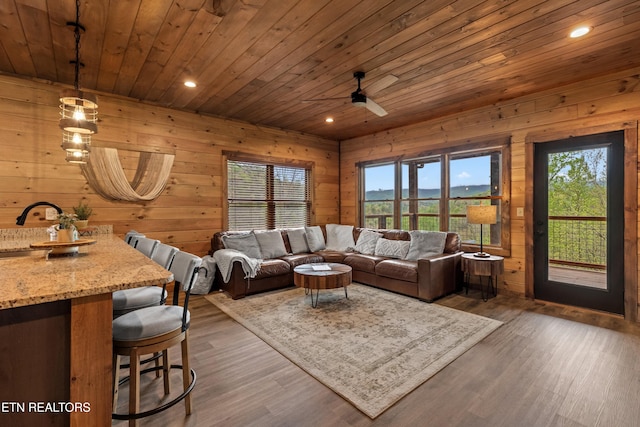 living area with wood finished floors, a wealth of natural light, a ceiling fan, and wooden ceiling