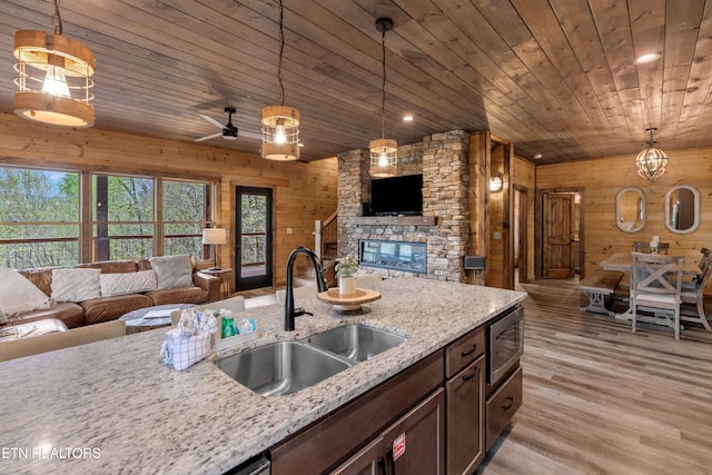 kitchen with a sink, open floor plan, wooden walls, wood ceiling, and stainless steel microwave