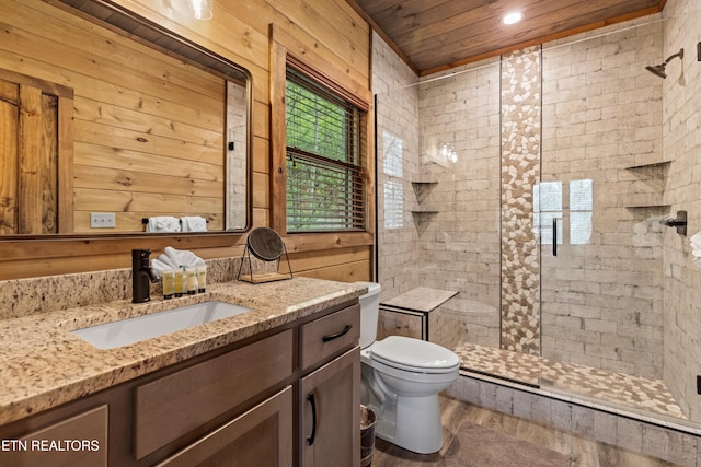 bathroom with toilet, wood finished floors, vanity, and a stall shower