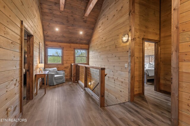 hall with an upstairs landing, wood finished floors, vaulted ceiling with beams, wooden ceiling, and wood walls