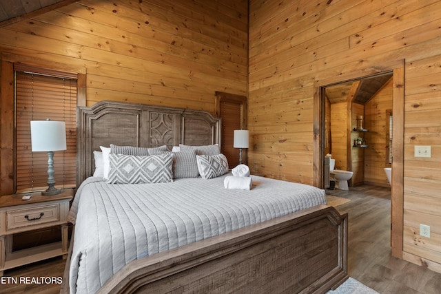 bedroom featuring wooden walls, wood finished floors, and connected bathroom