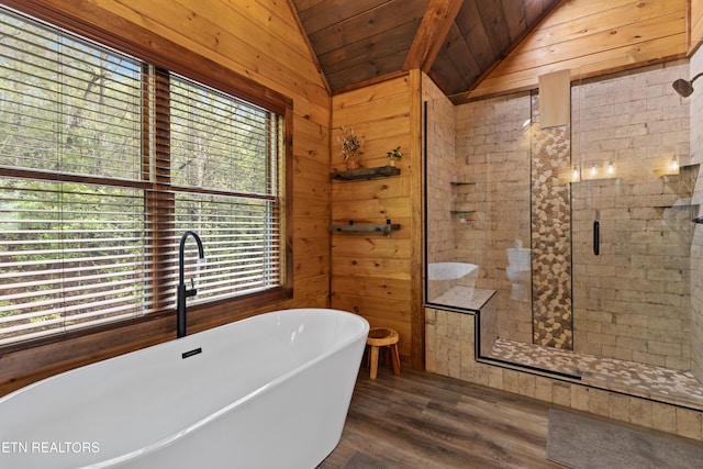 full bath with wood walls, wood finished floors, a stall shower, a freestanding bath, and lofted ceiling
