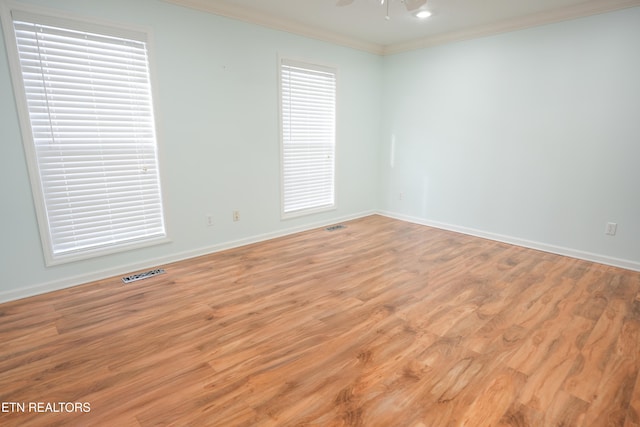 empty room with ceiling fan, crown molding, visible vents, baseboards, and wood finished floors