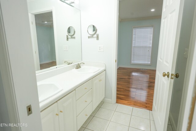 bathroom with ornamental molding, tile patterned flooring, a sink, and baseboards