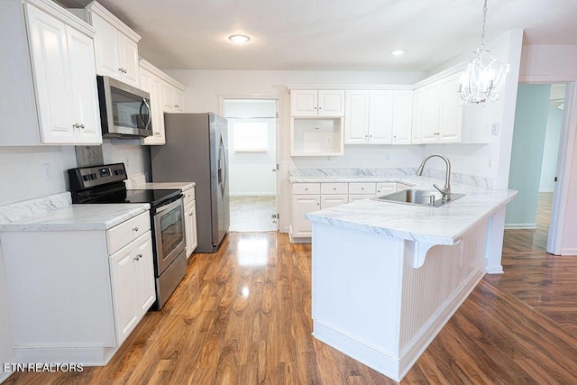 kitchen with appliances with stainless steel finishes, a sink, white cabinetry, a peninsula, and a kitchen breakfast bar