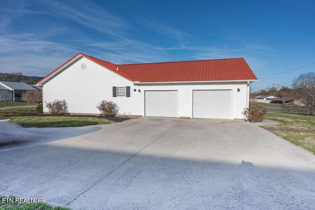 view of property exterior with a garage, driveway, and metal roof