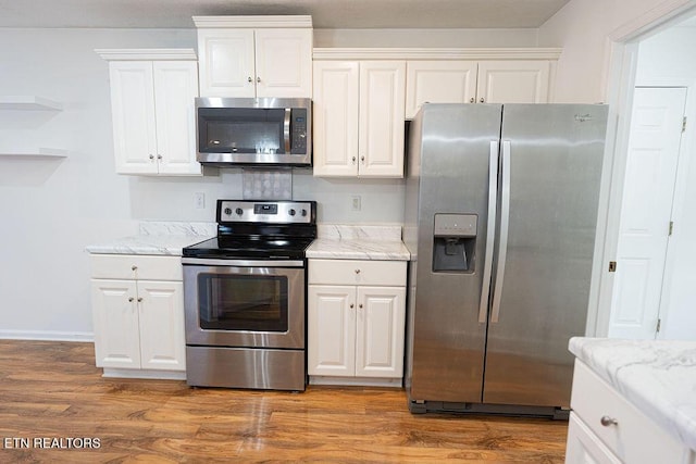 kitchen with stainless steel appliances, light stone counters, white cabinetry, baseboards, and wood finished floors