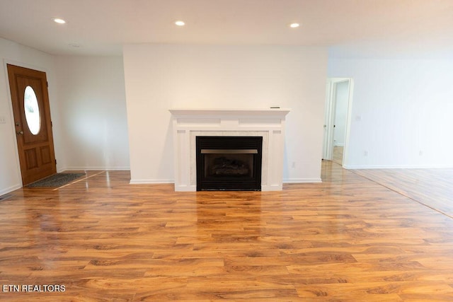 unfurnished living room featuring wood finished floors, recessed lighting, and baseboards