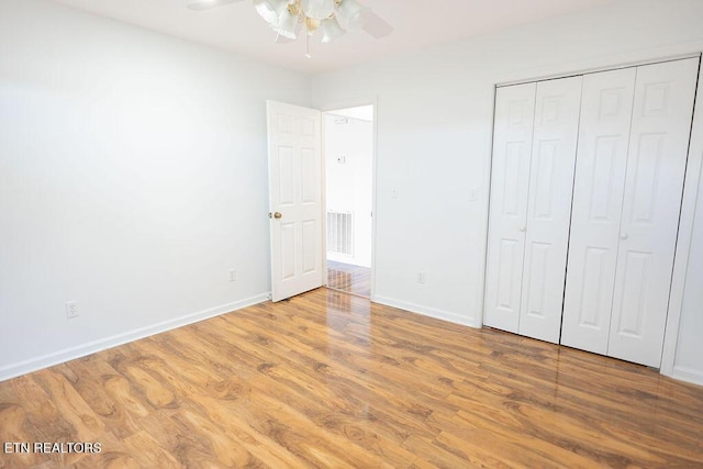 unfurnished bedroom featuring baseboards, visible vents, wood finished floors, and a closet