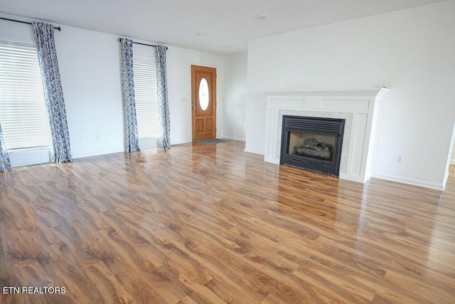 unfurnished living room featuring baseboards, wood finished floors, and a fireplace