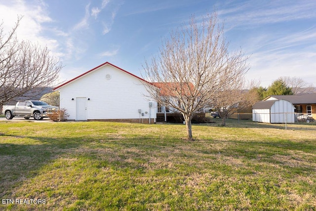 view of side of home with fence, a storage shed, an outdoor structure, and a lawn