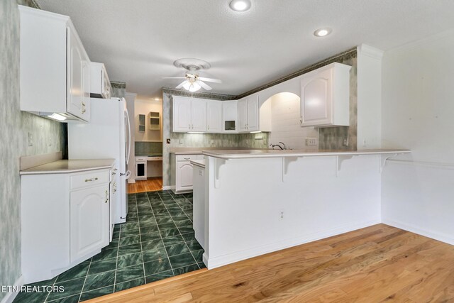 662 Laurel Cir, Crossville, TN 38555 - kitchen featuring a peninsula, freestanding refrigerator, white cabinetry, a ceiling fan, and a breakfast bar area