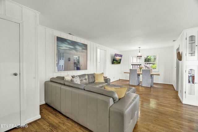 living area featuring dark wood-style flooring, visible vents, and a decorative wall