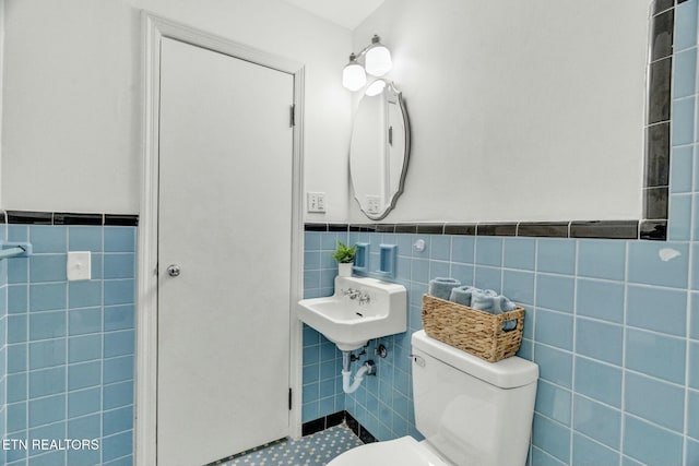 half bathroom featuring a wainscoted wall, toilet, and tile walls