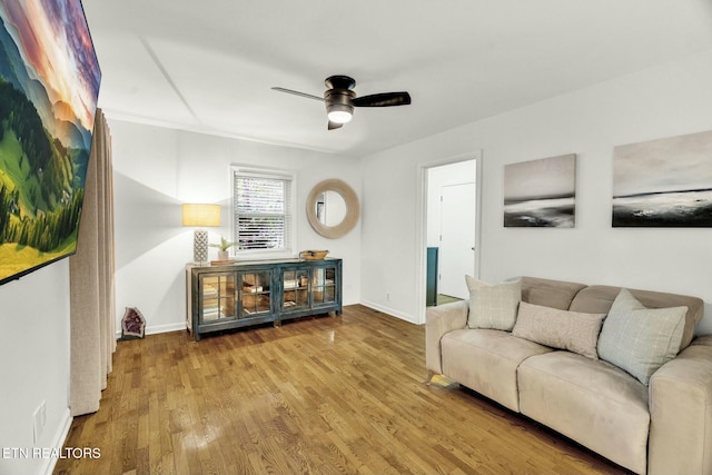 living area with baseboards, ceiling fan, and wood finished floors