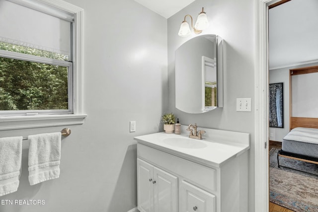 ensuite bathroom featuring vanity, connected bathroom, baseboards, and wood finished floors