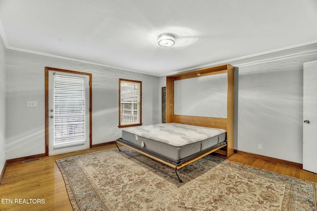 bedroom featuring crown molding, baseboards, and wood finished floors