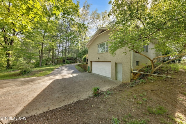view of property exterior featuring brick siding, driveway, and a garage