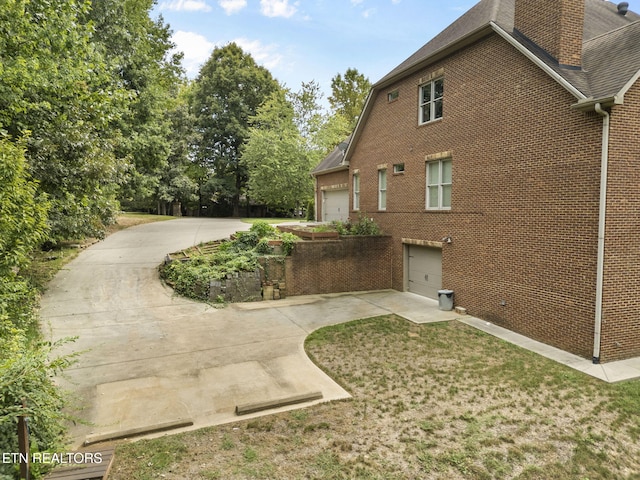 view of side of property with brick siding, a shingled roof, and a lawn