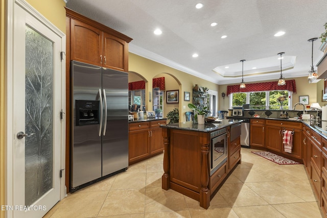 kitchen with ornamental molding, recessed lighting, a raised ceiling, decorative light fixtures, and stainless steel appliances