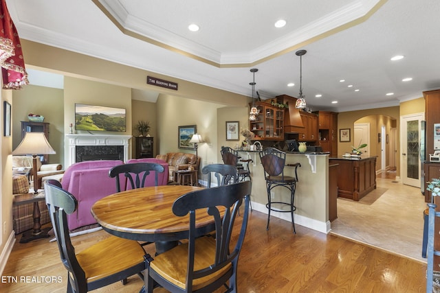 dining area featuring crown molding, arched walkways, a fireplace, and recessed lighting