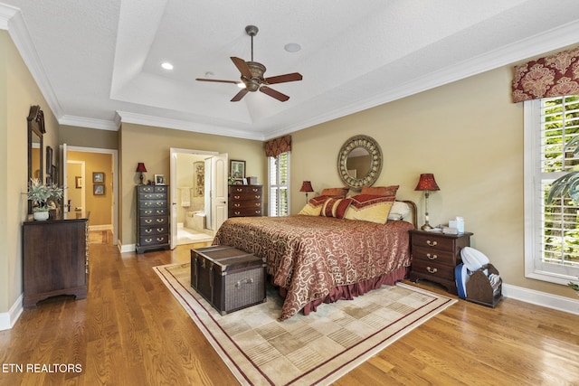 bedroom featuring baseboards, wood finished floors, and a raised ceiling