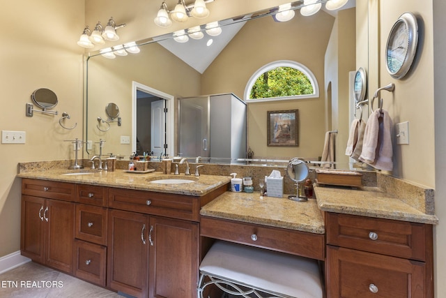 bathroom featuring double vanity, a sink, a shower with door, and lofted ceiling