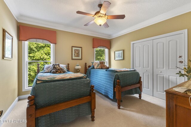 bedroom featuring crown molding, light carpet, a ceiling fan, baseboards, and a closet