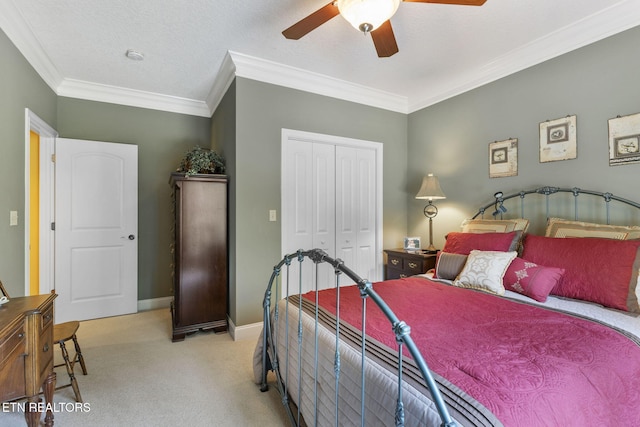 carpeted bedroom with a closet, a ceiling fan, baseboards, and crown molding