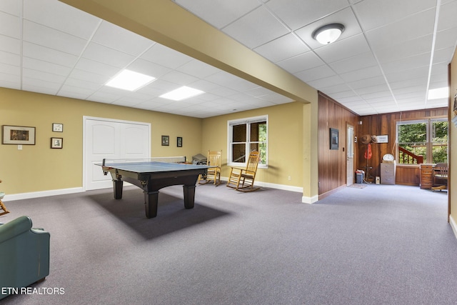 rec room featuring carpet flooring, baseboards, wood walls, and a paneled ceiling