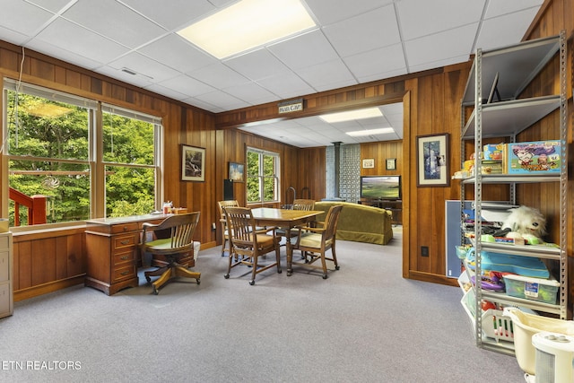 carpeted dining area featuring wooden walls