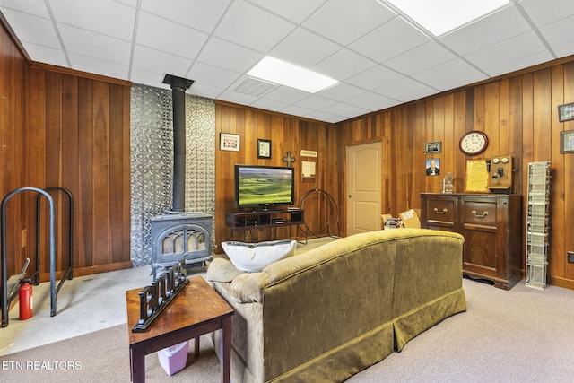 living area featuring wood walls, carpet, and a wood stove