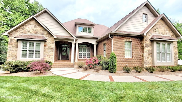 craftsman inspired home featuring stone siding and a front yard