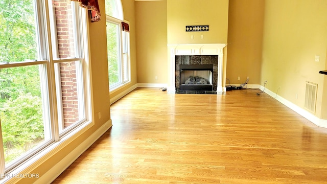 unfurnished living room featuring a tiled fireplace, baseboards, and a wealth of natural light