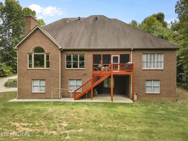 rear view of house with a patio, a chimney, brick siding, stairs, and a lawn